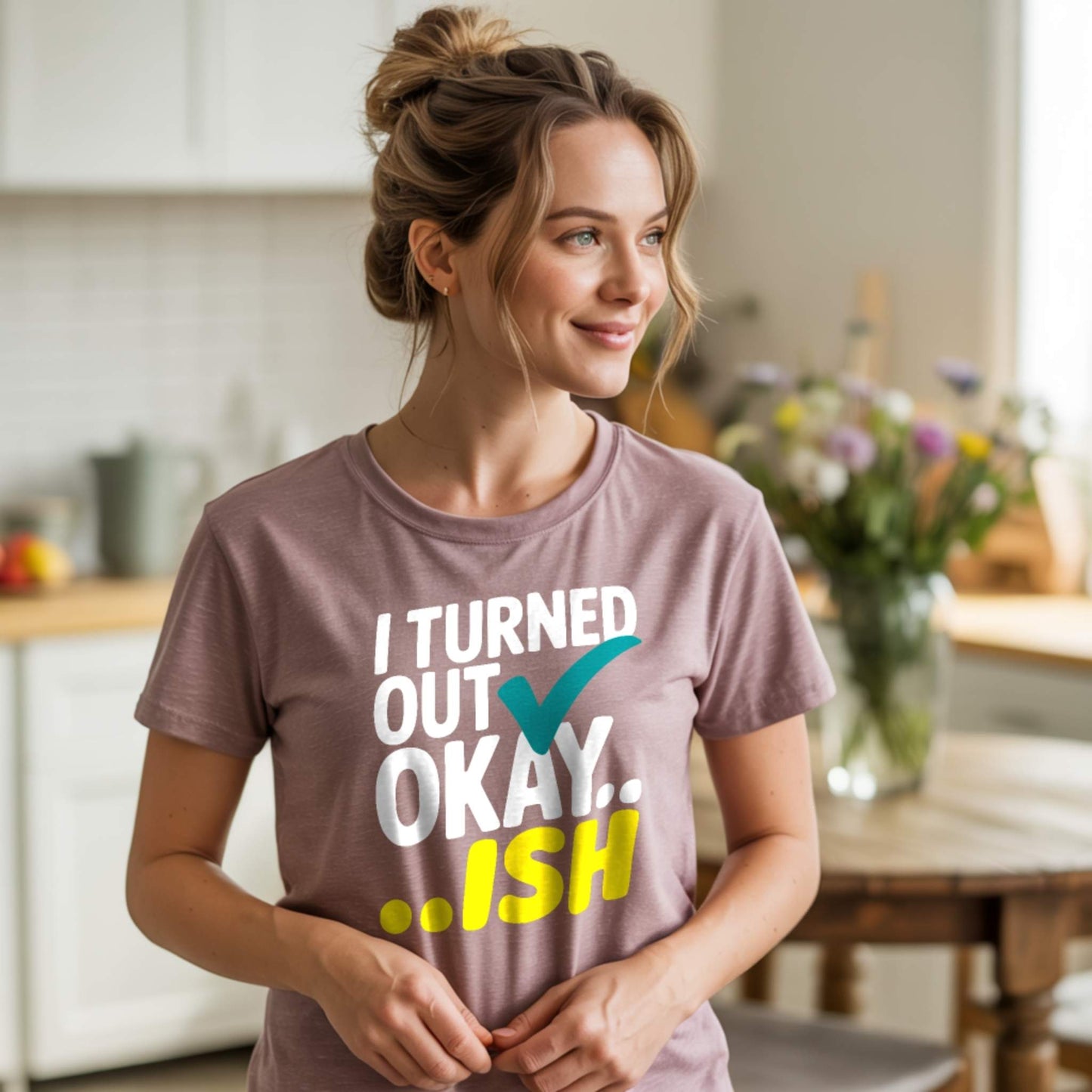 Woman in a Heather Mauve t-shirt with "I Turned Out Okay...ish" design, reflecting authentic parent mental health and humor.