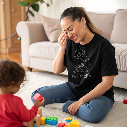 ParentingLOL Lifestyle: Joyful mom in a black "But first, coffee" tee, laughing at the chaos of parenthood while playing with her child.