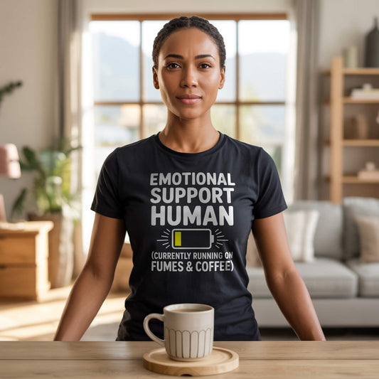 Product Hero Shot - Black Tee; Female model wearing a black "Emotional Support Human" t-shirt with a coffee mug, showcasing funny parenting and coffee lover vibes.