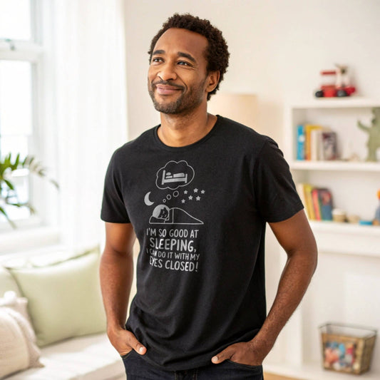 Man smiling in a black "I'm so good at sleeping" t-shirt, representing relaxed parent humor and everyday comfort.