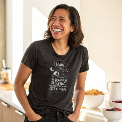 Woman laughing in a heather black "I'm so good at sleeping" t-shirt, perfect for relatable mom life and authentic parent humor.