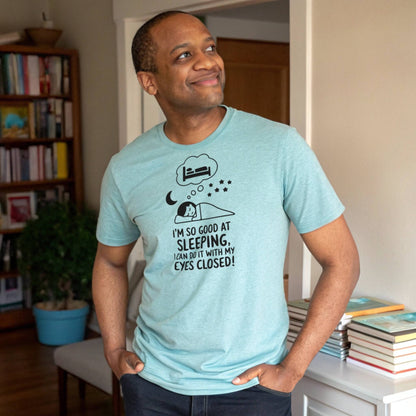 Man smiling in a heather clay "I'm so good at sleeping" t-shirt, embodying relaxed parent mental health and humor.