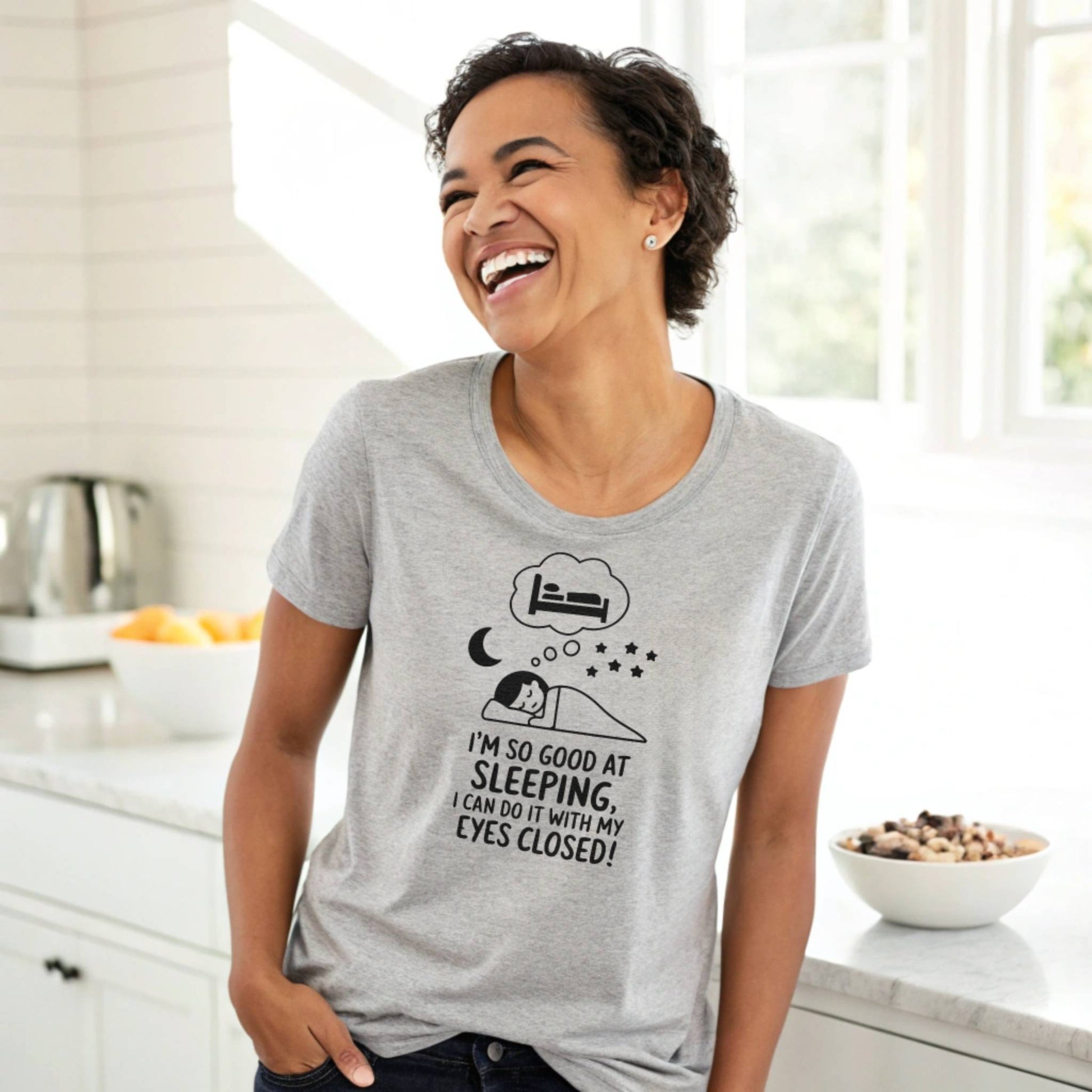 Woman laughing in a heather dust "I'm so good at sleeping" t-shirt, radiating joy and relatable mom life humor.