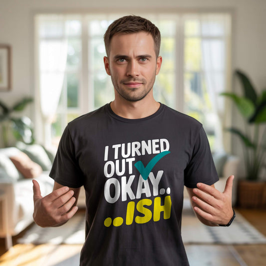 Man wearing a dark gray t-shirt with "I Turned Out Okay...ish" in white, teal, and yellow, a humorous parent statement.