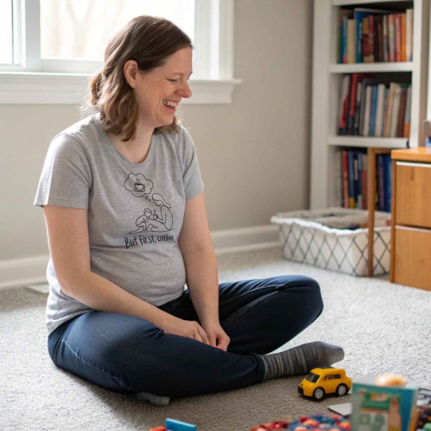 ParentingLOL Lifestyle: Happy mom in a heather dust "But first, coffee" tee, finding comfort and joy amidst parenting struggles.