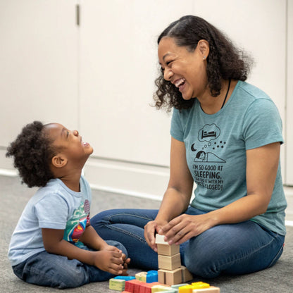 Mother and child playing, mom in a heather clay "I'm so good at sleeping" t-shirt, illustrating playful mom life and parent humor.