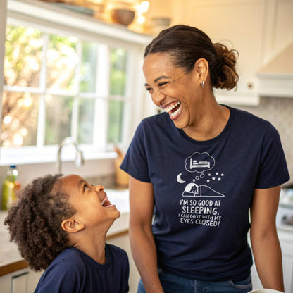 Mother and child laughing, mom wearing a navy "I'm so good at sleeping" t-shirt, capturing relatable mom life humor.